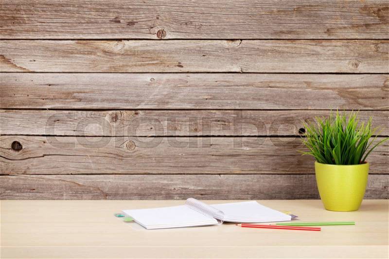 Office desk workplace with supplies and plant in front of wooden wall, stock photo
