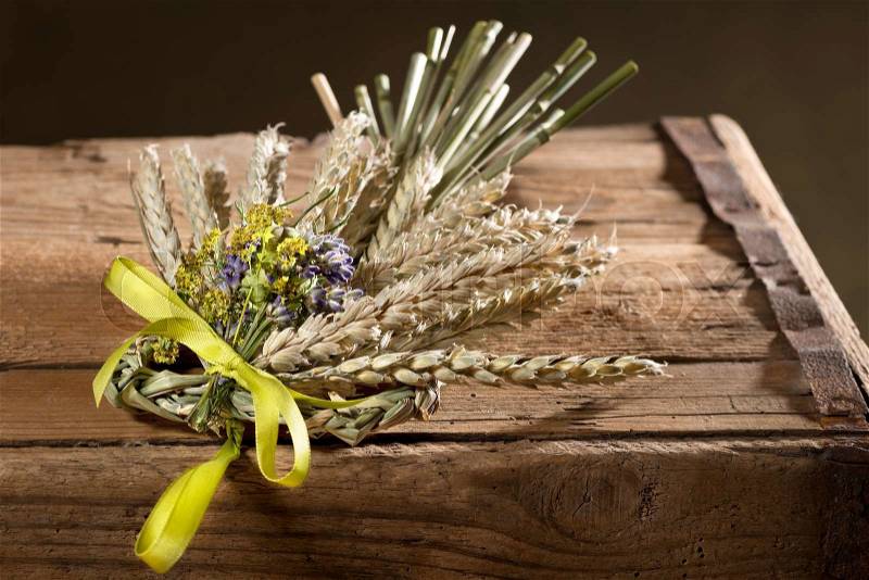Bundle of wheat with flower and band ojn the wooden desk, stock photo