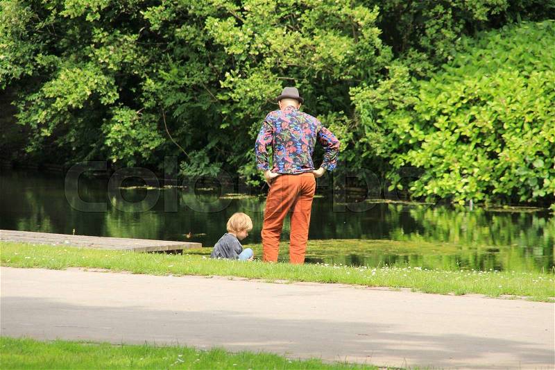 The father and his son discuter their problems along the pond in the park in the summer in the city Rotterdam, stock photo
