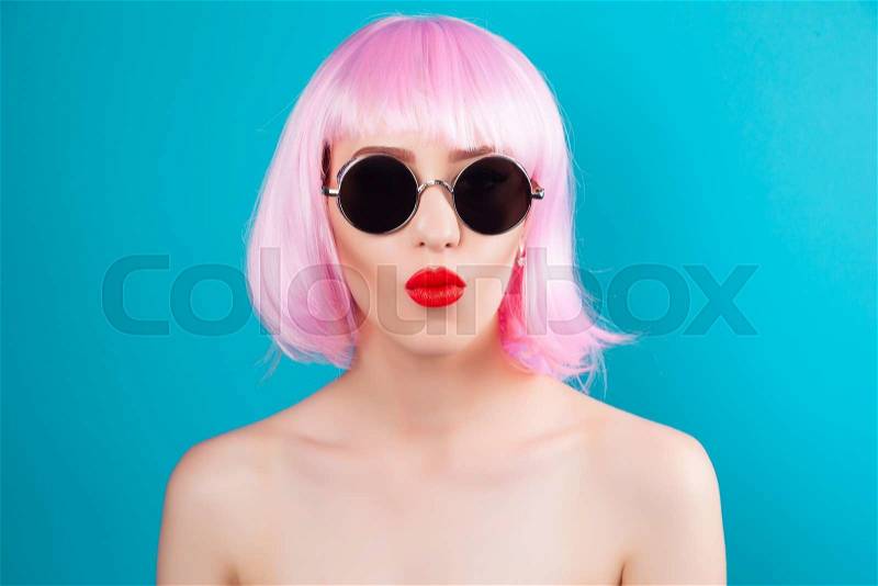 Beautiful woman wearing pink wig and sunglasses against blue background, stock photo