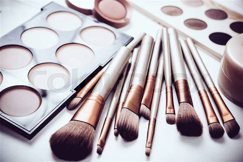 Professional makeup brushes and tools, natural make-up products set, eyeshadows and concealers on white table, stock photo