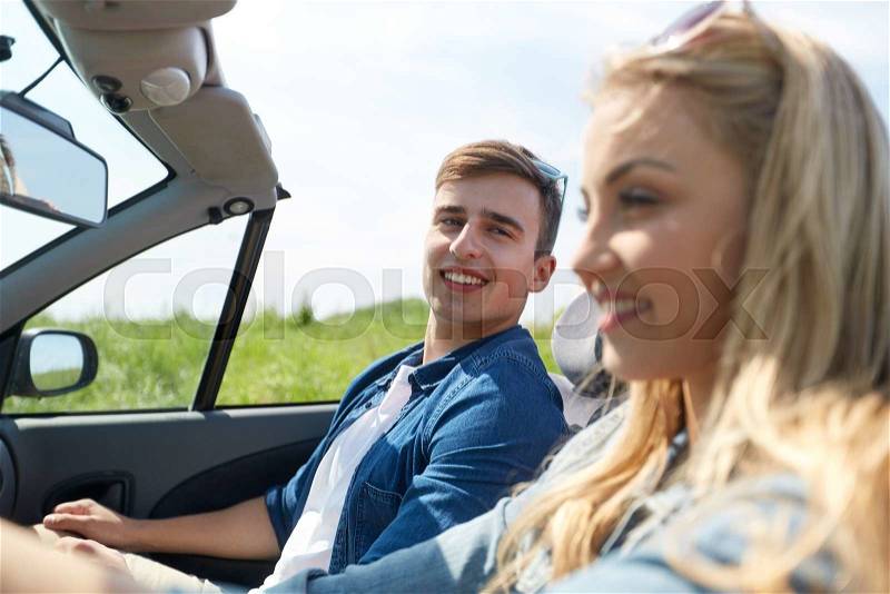 Leisure, road trip, travel and people concept - happy couple driving in cabriolet car outdoors, stock photo