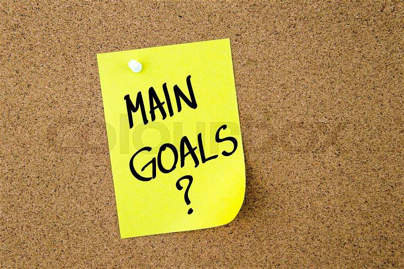 Main Goals ? written on yellow paper note pinned on cork board with white thumbtacks, copy space available, stock photo