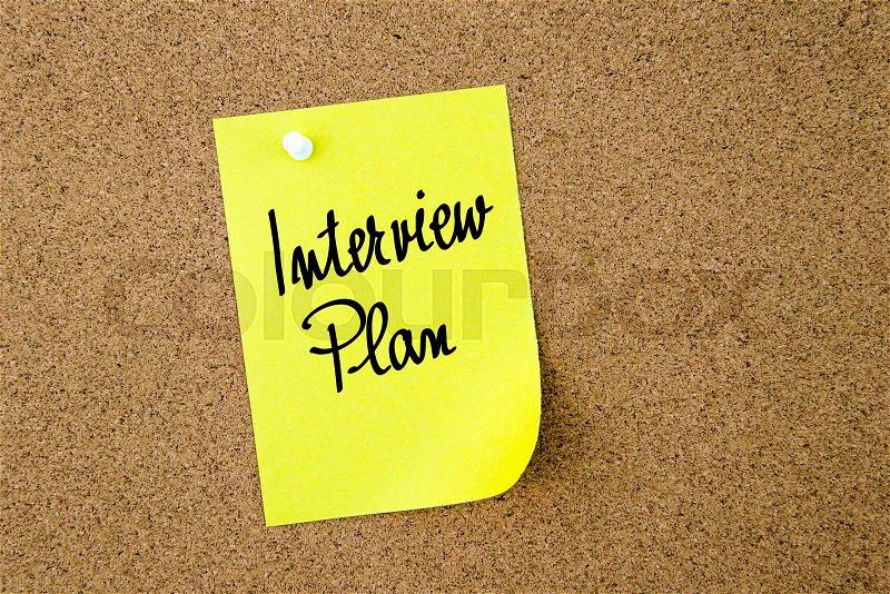 Interview Plan written on yellow paper note pinned on cork board with white thumbtacks, copy space available, stock photo