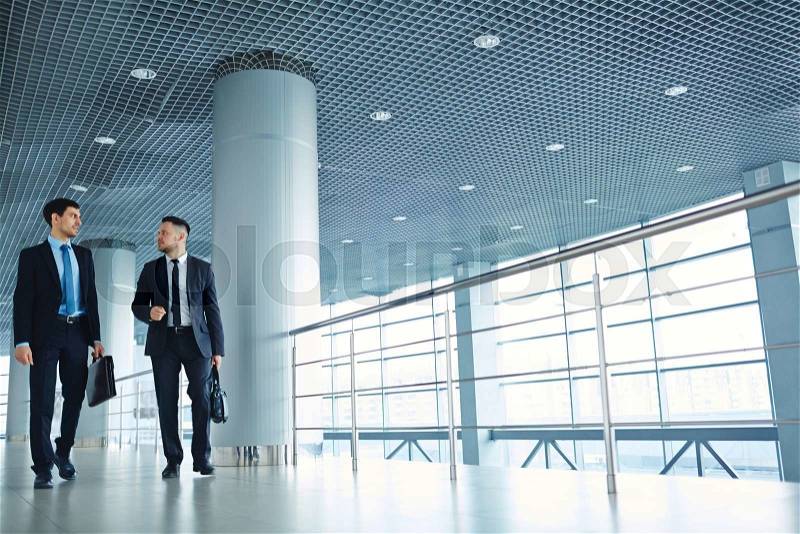 Two specialists walking down business center, stock photo