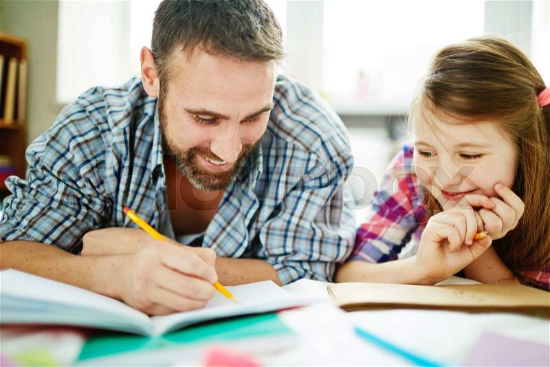 Happy man drawing in copy-book with his daughter near by, stock photo