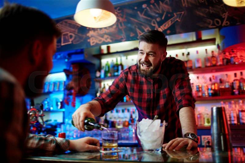 Young bearded barman working in pub, stock photo