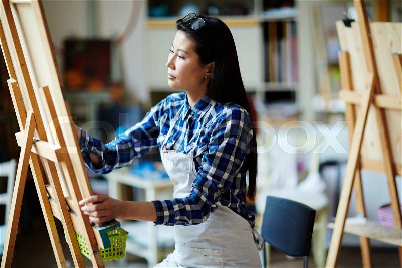 Creative student of arts drawing on easel in studio of arts, stock photo