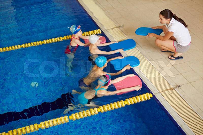 Little swimmers in water looking at their coach, stock photo