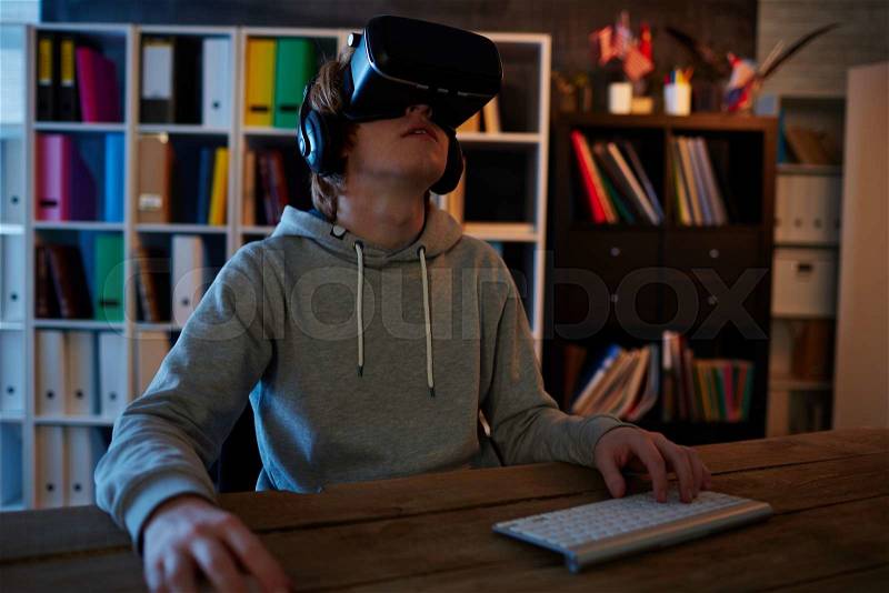 Teenage boy spending night playing videogames with vr glasses, stock photo
