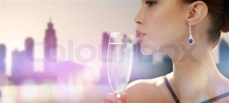 Holidays, nightlife, drinks, people and luxury concept - close up of beautiful young asian woman drinking champagne at party over city silhouette and lights background, stock photo