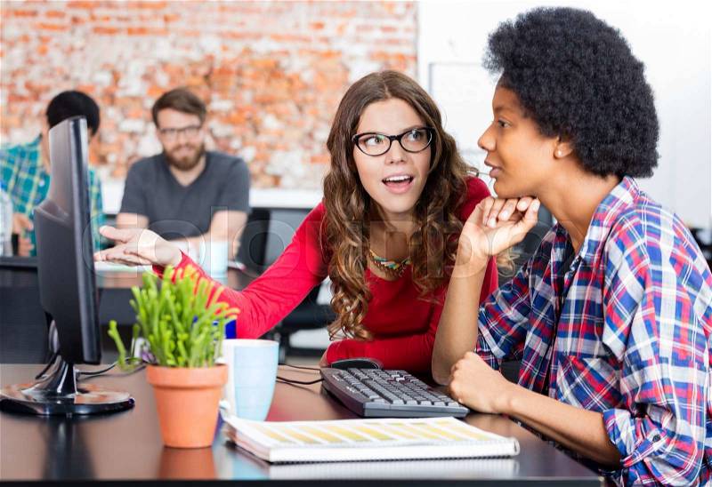 Two colleagues woman talking discussing sitting office desk computer business people working casual wear, stock photo