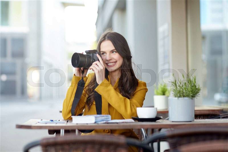 Travel, tourism, photography, leisure and people concept - happy young tourist woman or teenage girl photographing with digital camera photographing and drinking cocoa at city street cafe terrace, stock photo