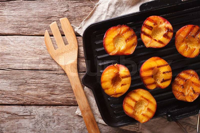 Summer dessert: Cooking Ripe peaches on a grill pan on the table close-up. Horizontal view from above , stock photo