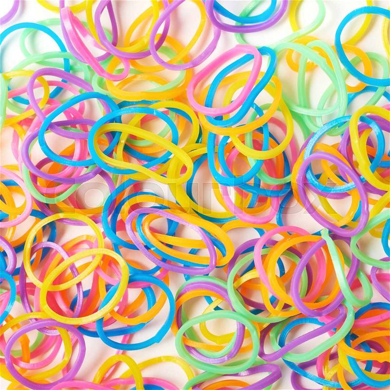 Surface covered with multiple colorful resin loom bands over the white background, stock photo