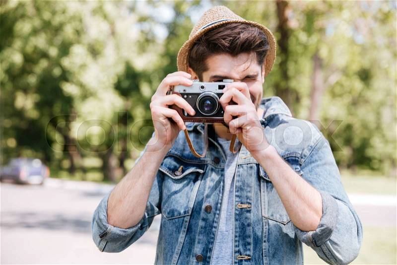 Happy casual hipster man making photo using camera outdoors, stock photo