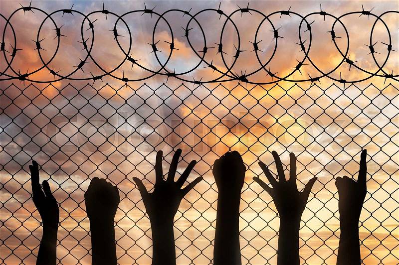 Refugees hands silhouette near the fence of barbed wire. refugee concept, stock photo
