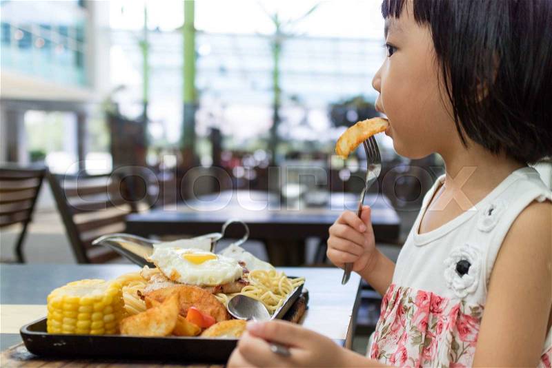 Asian Little Chinese Girl Eating Western Food in Outdoor Cafe, stock photo