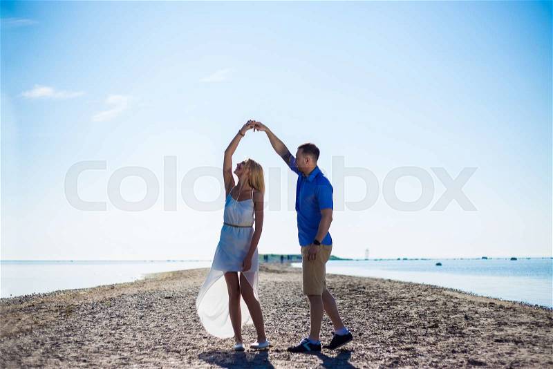 Portrait of beautiful couple in love dancing on summer beach, stock photo