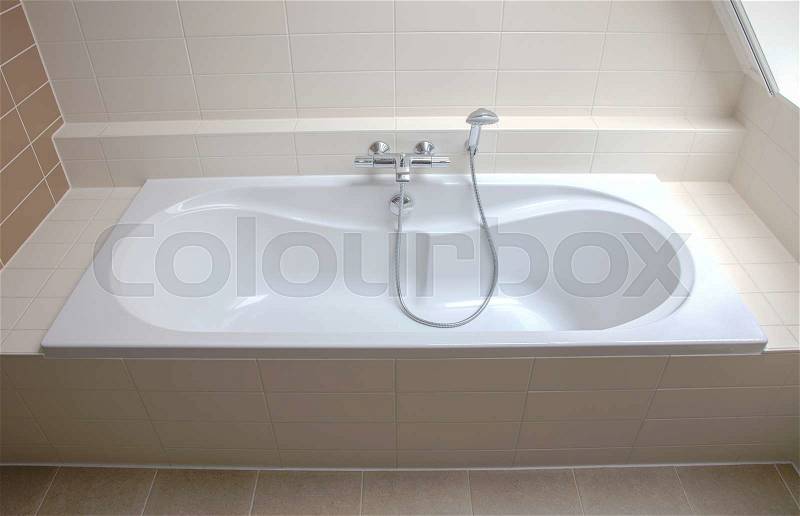 Modern white bathtub in a tiled bathroom, stock photo
