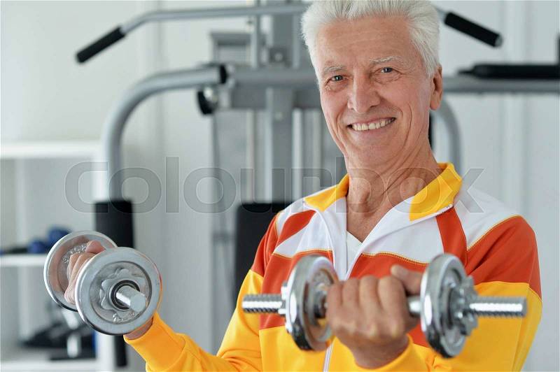 Elderly man in a gym during exercise, stock photo