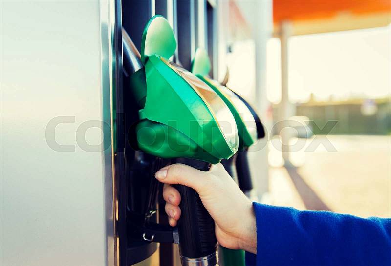 Object, fuel, oil, tank and transport concept - close up of hand holding gasoline hose at gas station, stock photo