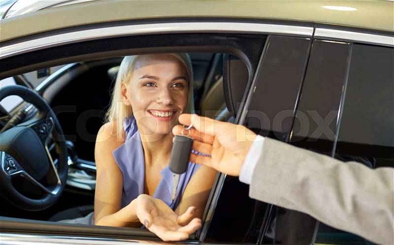 Auto business, car sale, consumerism and people concept - happy woman taking car key from dealer in auto show or salon, stock photo