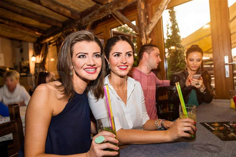Young beautiful women with cocktails in bar or club having fun, stock photo