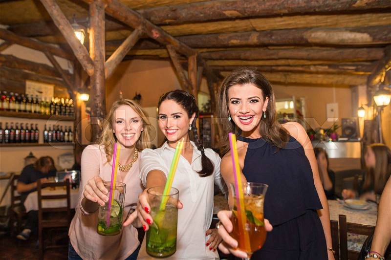 Young beautiful women with cocktails in bar or club having fun, stock photo