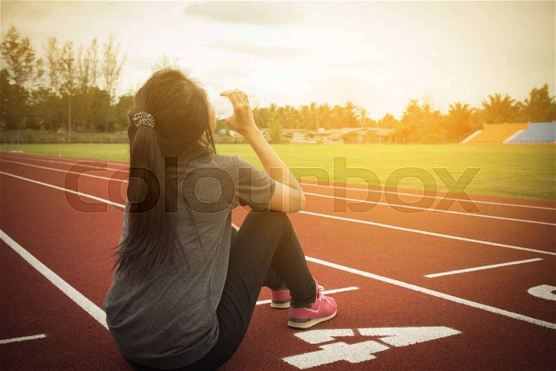 Woman drinking water on running track. Vintage tone, stock photo