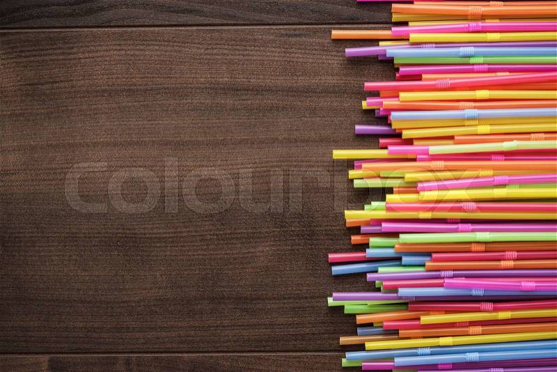 Colorful striped bendy cocktail straws on wooden table, stock photo