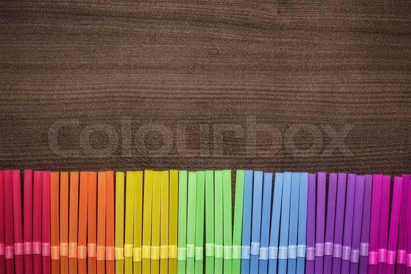 Colorful striped bendy cocktail straws on wooden table, stock photo