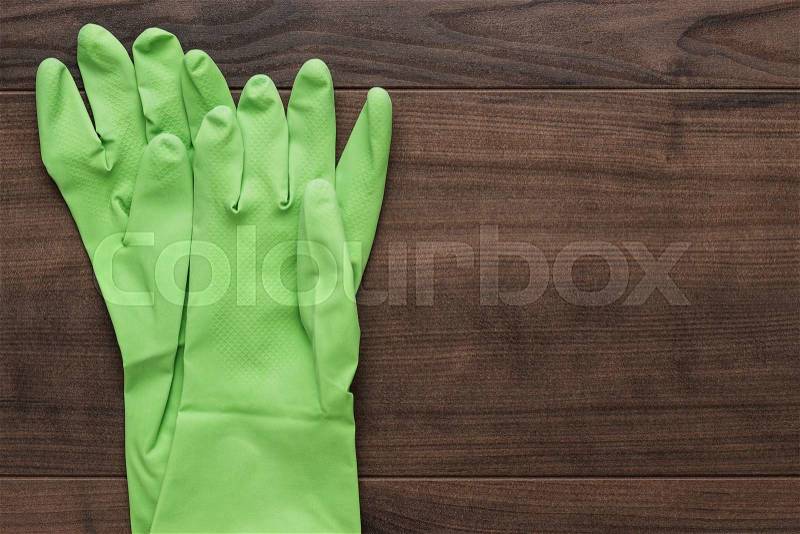 Green rubber cleaning gloves on wooden background, stock photo
