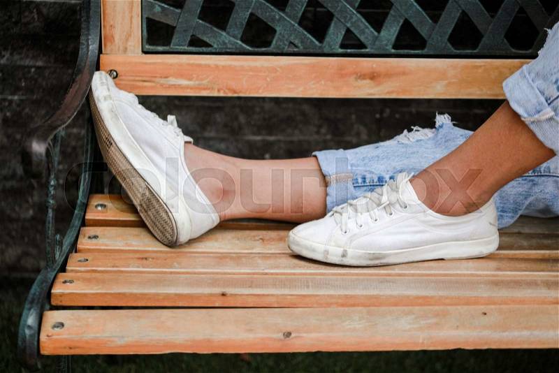Woman\'s feet relaxing on bench in the park, stock photo