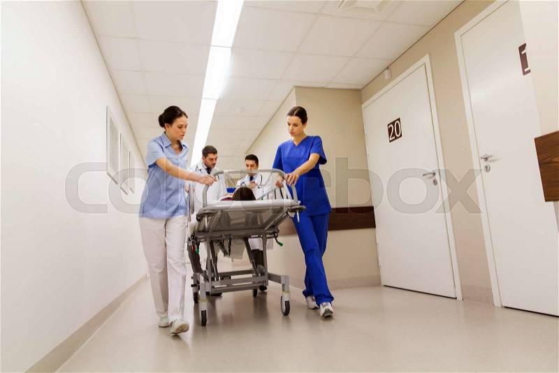 Profession, people, health care, reanimation and medicine concept - group of medics or doctors carrying unconscious woman patient on hospital gurney to emergency, stock photo