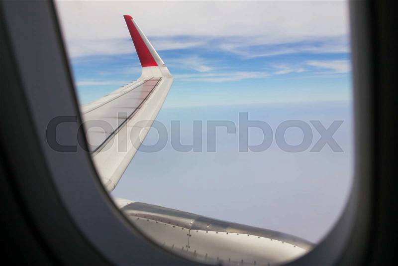 Looing at clouds and blue sky through window of an aircraft, stock photo