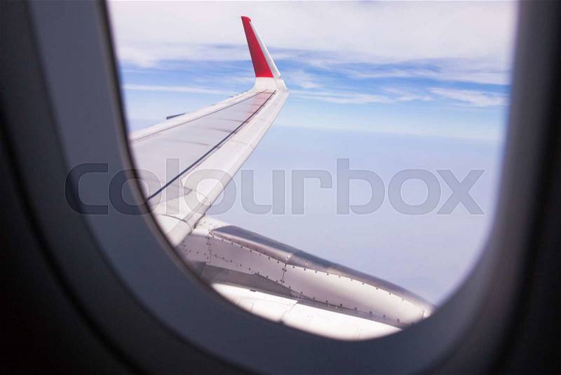 Looing at clouds and blue sky through window of an aircraft, stock photo