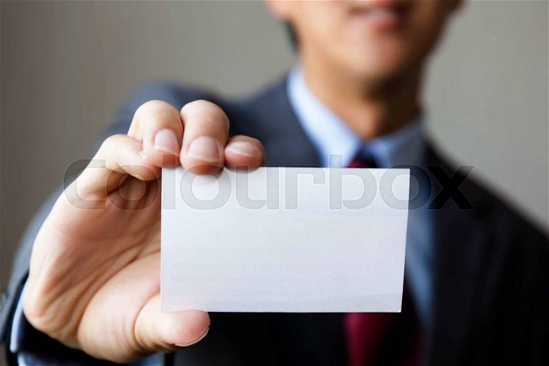 Young man in business suit holding white blank business card. Business name card presenting (mock up white card), stock photo