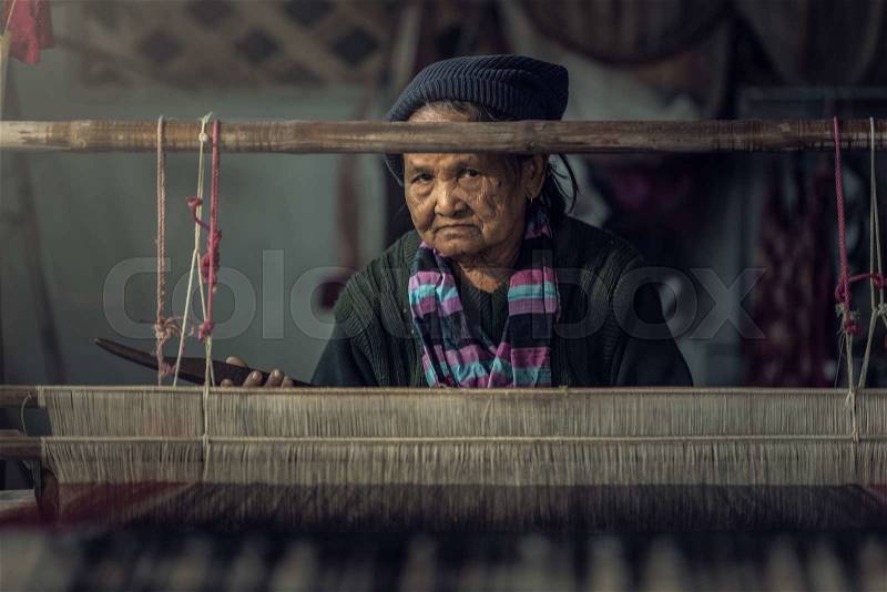 Old women demonstrate to procedure of making Thai Silk weaving, stock photo