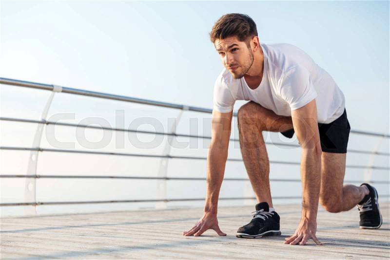 Concentrared young sportsman is ready to run outdoors in the morning, stock photo