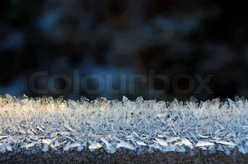 Close-up of a border with ice crystals against a dark background, stock photo
