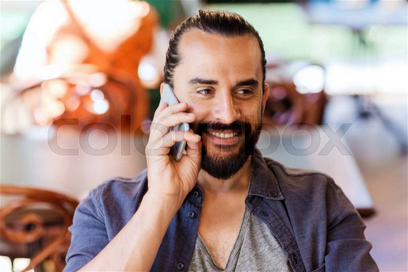 People, communication and technology concept - happy man calling on smartphone at bar or pub, stock photo