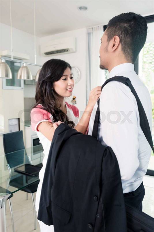 Wife helping her man going to office for work binding his tie for nice attire, stock photo