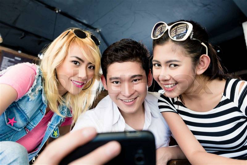 Group of Asian women and man making selfie with phone, stock photo