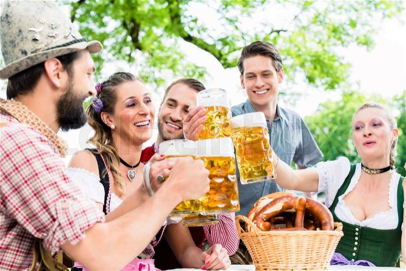 Clinking glasses with beer in Bavarian pub, stock photo