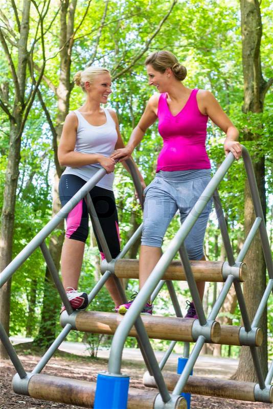Two women, one pregnant, at fitness sport in climbing park, stock photo