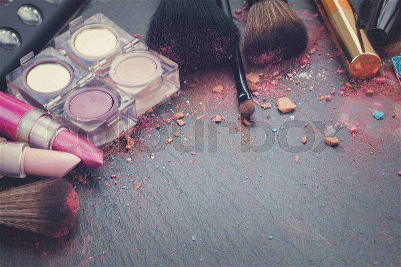 Two pink lipsticks and eye shadows on black background with copy space, retro toned, stock photo