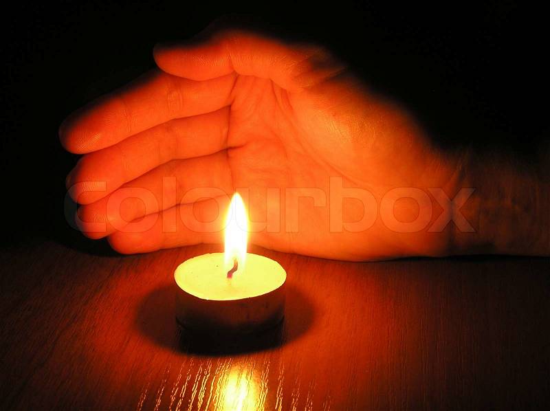 On a photo the candle which protects a palm of the person. A photo on a dark background. The photo is made in Ukraine, stock photo