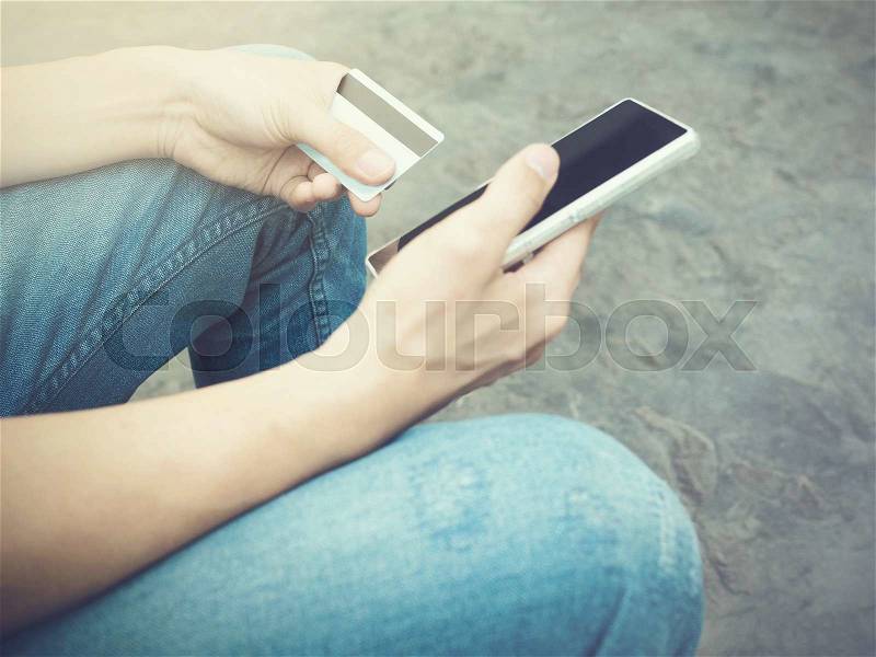 People holding a credit card and using smartphone to make mobile payment. (focus on credit card), stock photo