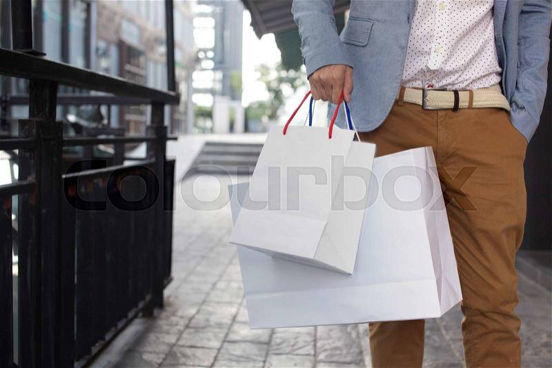 Shopaholic man walking on commercial street with a lot of shopping bags, stock photo